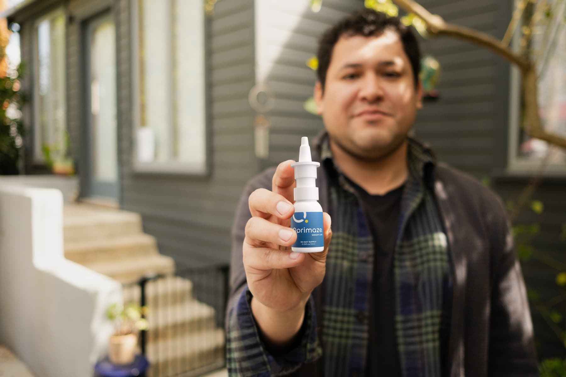 Man holding up the Oprimaze Weight Loss nasal spray