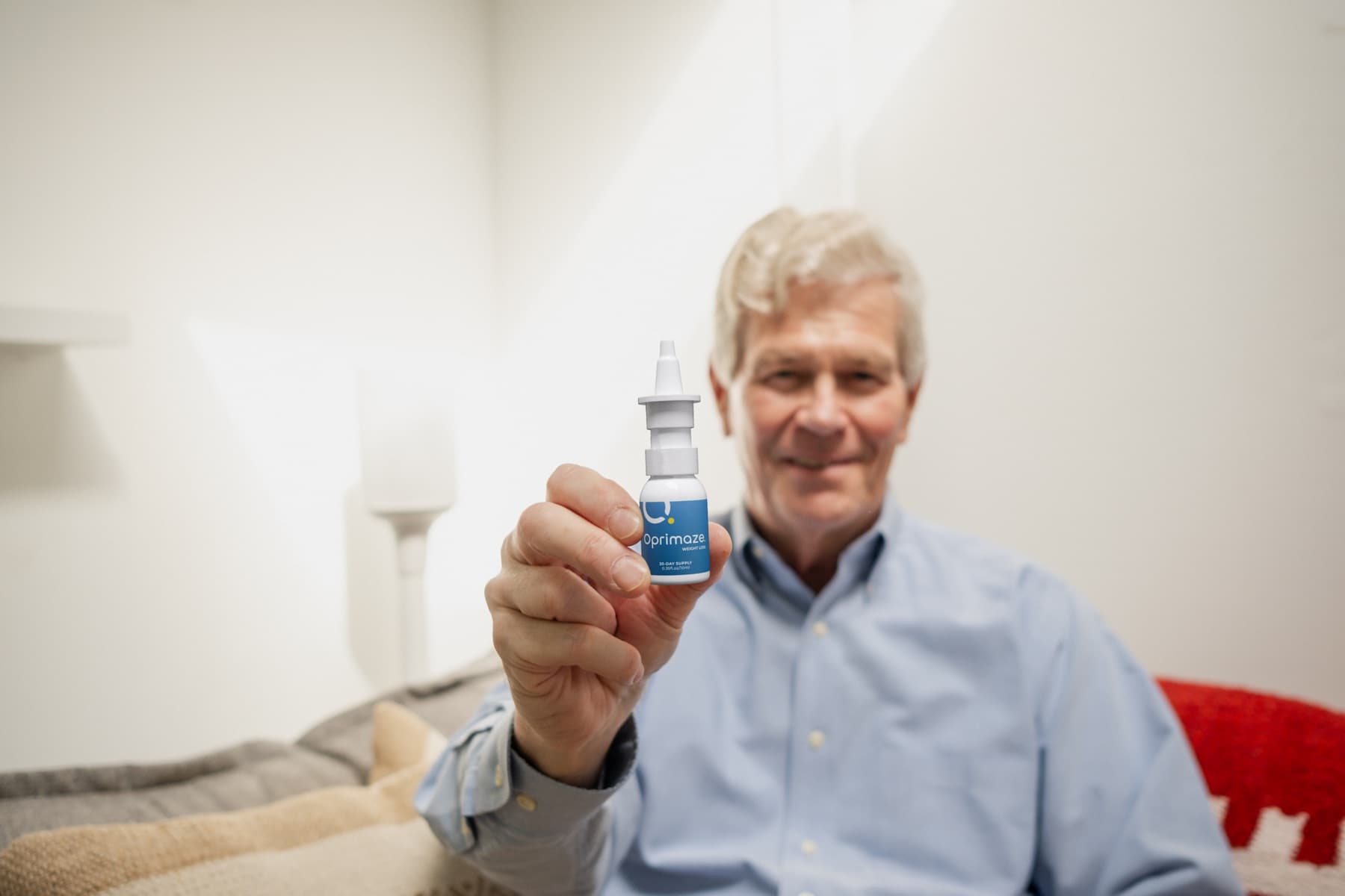 Man holding the Oprimaze Weight Loss nasal spray at home